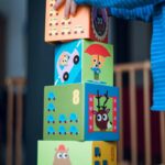 Child stacking large, colorful blocks.