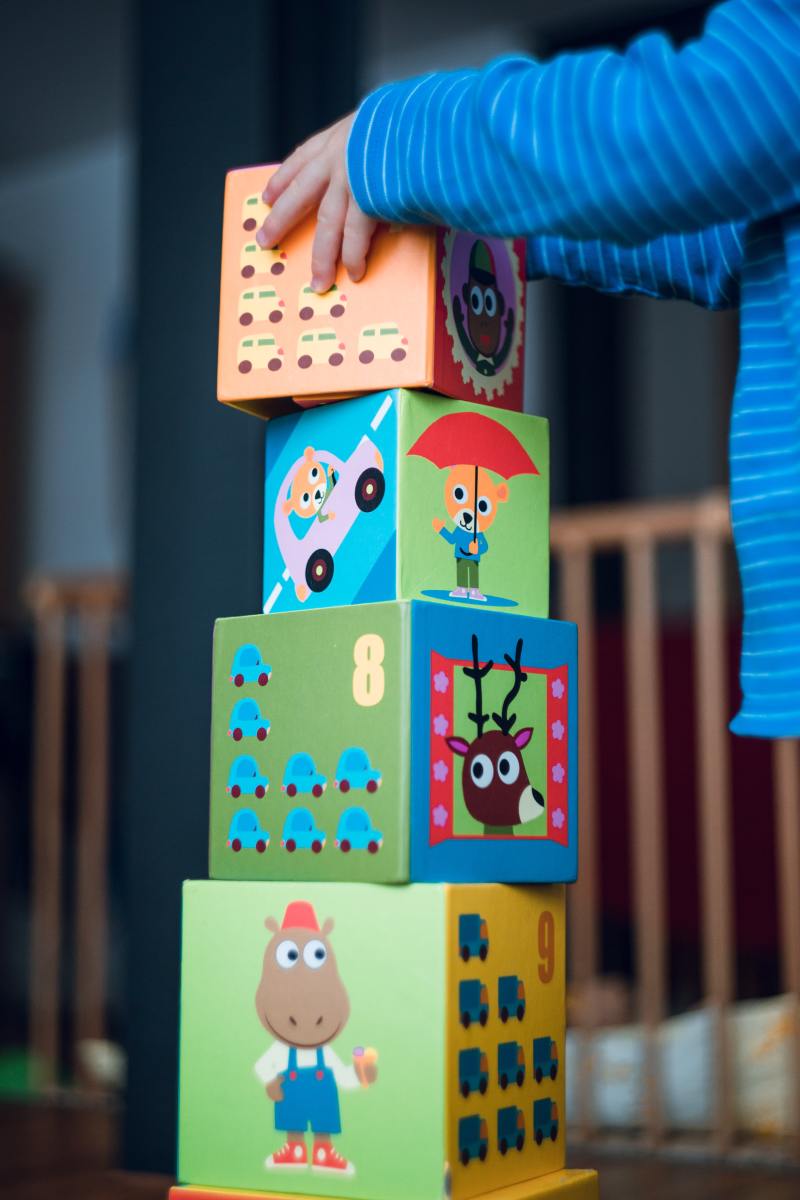 Child stacking large, colorful blocks.